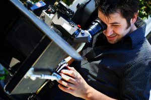Young man operating camera and pulling his own focus. 35mm motion picture camera.